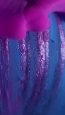 Dikey video. Duman boyası. Emülsiyon damlası. Pembe mor duman soyut mavi küre akıyor, parıldıyor, çizgili yüzey, su çözünmüş arka plan..