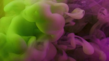 Mürekkep dalgası. Dumanı karıştır. Mor yeşil boya sıvıya dökülüyor. Sanat karışımı renk girdabı patlaması soyut akış odaklanmamış arkaplan.