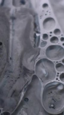 Dikey video. Mürekkep katmanları. Yağ sıvısı. Kirli yüzeyde yüzen gri beyaz siyah pigment. Odaklanmamış grunge harmanı şeffaf nokta soyut arkaplanı.