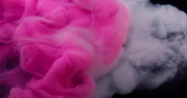 Karışım akışı. Atmosferik duman. Soyut koyu siyah arkaplana yayılan, suda dönen dumandaki pembemsi mavi mürekkep..