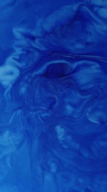 Dikey video. Mermer diş minesi. Boya emülsiyonu. Sanat mavisi damlalar yüzeye dökülür. Sıvı boya sızıntısı soyut arka plan dekoratif girdap sıçraması.