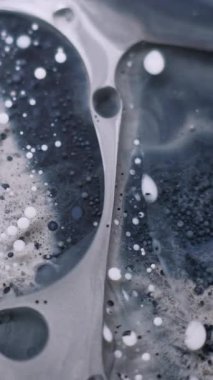 Dikey video. Akrilik kütle. Kabarcık emülsiyonu. Pigment parçacıkları grunge suyunda yüzüyor. Gri siyah mürekkep damlası patlaması karışık bulanık arkaplan.