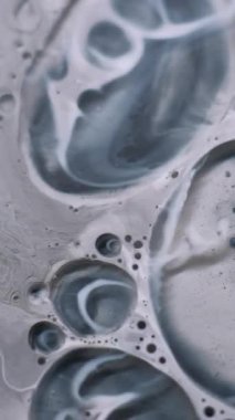 Dikey video. Yağ sıvısı. Boya dokusu. Odaklanmamış siyah beyaz mürekkep damlası yuvarlak lekesi. Girdap eğrisi jel dökülmesi baloncuk soyut sanat arka planı.