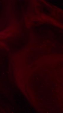 Dikey video. Mistik akış. Duman patlaması. Kırmızı pembe mürekkep resimleri sanatsal emülsiyon yayıyor. Renkli su soyut arkaplan bulanık siyah parıltı.