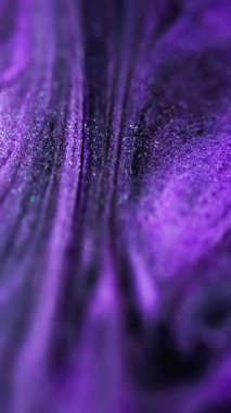 Dikey video. Boya dökülmüş. Işıldayan sıvı. Odaklanmamış mor siyah renkli parlak desenli mürekkep dalga hareketini soyut sanat arka planına sıçratıyor.