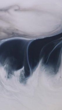 Dikey video. Enamel akışı. Grunge sıvısı. Beyaz boya dokusuna karışık gri leke spreyi. Kirli siyah dalga soyut arkaplan.