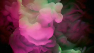 Duman akışı. Neon mürekkebi. Pembe yeşil dumanlı patlama. Sanat sıvısında karışan kıvrımlı kıvrımlı renk. Siyah sıvı soyutlanmış arkaplan.