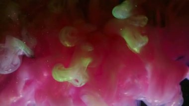 Sis sıvısı. Parıldayan dalga. Neon parlak boya sisi suda çözülüyor. Siyah arkaplan parlaklığında pembe yeşil duman soyut bulanık karışımı.