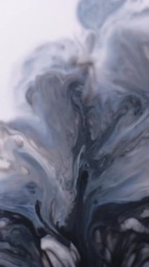 Dikey video. Karışık mürekkep katmanları. Sanat dalgası. Kirli beyaz sıvı yüzeyden fışkıran gri mavi pigment. Odaklanamayan grunge şekilsiz nokta nemi soyut arkaplan.