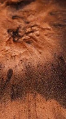 Dikey video. Mürekkep döküldü. Parıldayan patlama. Turuncu lav püskürmesi volkanı. Erimiş bakır kütle karışımı siyah sıvı soyut arkaplan boyunca.