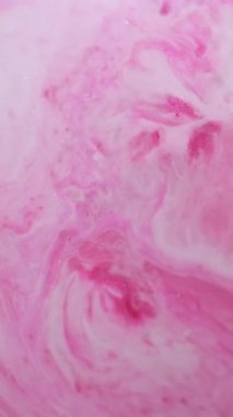 Dikey video. Parlak bir karışım. Parıltı seli. Parlak pembe metal tozları parlatıcı sıvının içinde. Sanat dekoratif tuhaf akış lüksü soyut bir arkaplanı ateşliyor.