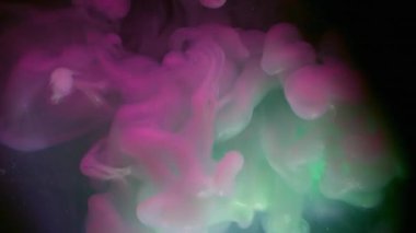 Duman akışı. Neon mürekkebi. Mor yeşil dumanlı patlama. Parlayan sıvıyla harmanlanmış renk. Siyah kozmik soyut odaklanmış arkaplan.