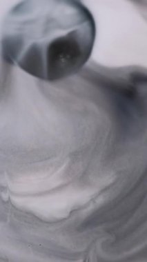 Dikey video. Enamel fırıl fırıl dönüyor. Grunge akıntısı. Gri mermer mürekkep, beyaz, ıslak, soyut arka plan yüzeyine yayılır. Monokrom siyah sızıntıya odaklanmış..