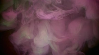 Sis sıçraması. Dumanı karıştır. Pembe yeşil boya sıvısı siyah bulanık dokuya dökülüyor. Sanat karışımı renk soyut akış odaklı olmayan arkaplan.