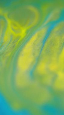 Dikey video. Bulanık boya sıçraması. Sis girdabı. Odaklanmamış mavi yeşil renkli duman dokusu mürekkep harmanı hareket soyut sanat arkaplanı yayıyor.