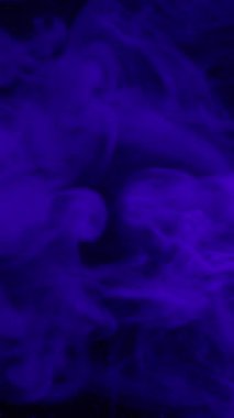 Dikey video. Mistik akış. Duman patlaması. Mavi menekşe mürekkep resimleri sanatsal emülsiyon yayıyor. Karanlık su soyut arkaplan bulanık siyah parıltı.