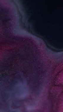 Dikey video. Köpüklü sıvı. Boya girdabı. Gri mermer sıvı yüzey üzerinde yüzen pembe mor parıltı tozu soyut arka planda olağanüstü bir şekilde yer değiştirmiş..