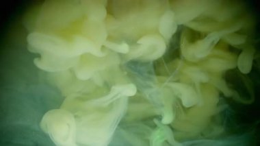 Su altı boyası. Haze girdabı. Soyut sıvıda sarı sisli akış mürekkebi. Siyah arkaplanda fantezi bulanık renk damlası karışımı.