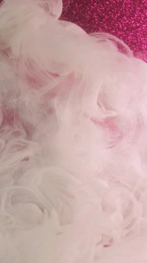 Dikey video. Su patlaması. Duman karışımı. Odaklanmamış beyaz renk parlayan sıçrama pembe parıldayan soyut sanat ışığı arka planında yüzen boya mürekkep deseni sisi.