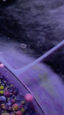Dikey video. Çok renkli sıvı. Kabarcık boyası. Katmanlı yağ lekesi, menekşe sarısı, pembe, gri, köpüklü mürekkep dumanın üzerinde yüzüyor, parlayan su soyut arka plan yüzeyi..