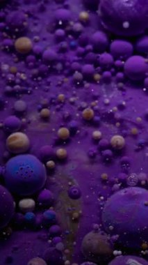 Dikey video. Yağlı boya. Köpüklü sıvı. Renkli sıvı karışımı köpürüyor. Dalganın çözünmüş menekşe galaksi mermerleri soyut arka planda parıldıyor.