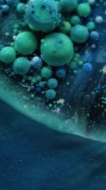 Dikey video. Yağlı boya. Renkli sıvı. Sanat akışı katmanları küçük parçacıkları boyar. Mistik parıldayan mavi yeşil sıvı soyut arkaplan.