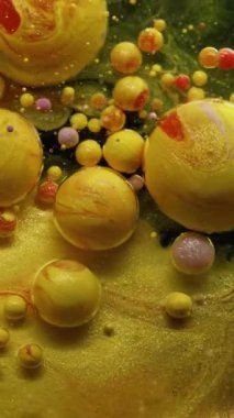 Dikey video. Pigment parıltısı. Kabarcık boyası. Mermer kıvrımlı yağ akıntısı karışım köpüklü sarı altın damlalar. Soyut su arkaplanı yuvarlak parçacıkları dökülüyor.