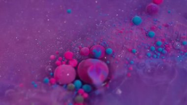 Akrilik parçacıklar karışır. Yüzen mürekkep. Pembe mor yağ damlaları ışıldayan parlak sıvılarda akıyor. Çoklu renk karışımı bulanık arkaplan.