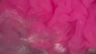 Parıltı yayılıyor. Boya girdabı. Parıldayan sanat parçacıkları su akar. Neon rengi emülsiyon patlaması pembe beyaz gümüş soyut arkaplan.