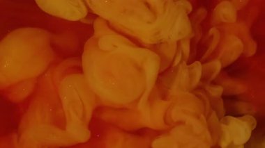 Mürekkep darbesi. Duman boyası. Kırmızı köpüklü suya turuncu dalga pigmenti döküldü. Renk akışı çözünmüş boya soyut kıvrım arkaplanını çözer.