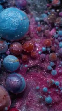 Dikey video. Işıldayan akış. Parlak boya damlası. Köpüklü su içinde çözünen renkli akrilik jel. Yaratıcı sıvı karışımı soyut arka plan köpük dokusu.