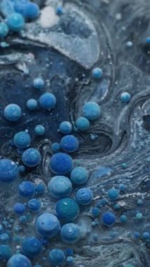 Dikey video. Grunge akışı. Kabarcık mürekkebi. Yüzen mavi jel damlalarını karıştıran gizemli, gri, siyah su. Dalgalı akan renkli soyut arkaplan.