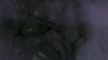 Mürekkep darbesi. Duman boyası. Mor köpüklü suda siyah dalga pigmenti döküldü. Renk akışı boyası odaklanmış kozmik soyut kıvrım arkaplanı.