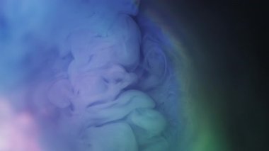 Mürekkep sıçraması. Sis sanatı. Odaklanamayan mavi renk, parlak sıvı gökkuşağı deseni soyut koyu siyah arkaplanda yayılıyor..