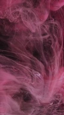 Dikey video. Sis girdabı. Boya su sıçratır. Odaklanmamış pembe boya sisi yüzen dalga koyu siyah soyut sanat arka planında hareket olduğunu gösteriyor.
