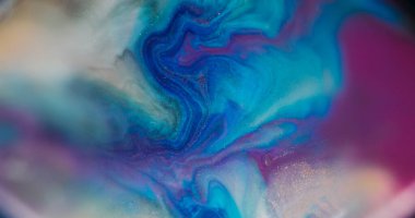 Görünmez mürekkep karışımı. Parlak sıvı. Odaklanmamış altın mavisi mor renkli ışıl ışıl parçacıklar soyut akrilik sanat arka planına dökülüyor..