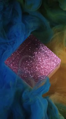 Dikey video. Akrilik boya dökülmüş. Mürekkep karışımı. Parlak sarı çok renkli duman dokusu ışıl ışıl parlayan küp bulutu sanat mor parlak ışık arka planında yüzüyor.