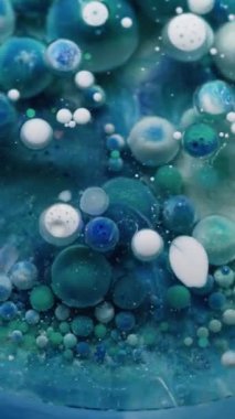 Dikey video. Yağ pigmenti düşüyor. Mürekkep patladı. Kabarcık jeli boyası renkli bulutlu suda çözünür. Yaratıcı sıvı karışımı soyut arka plan köpük yüzeyi.