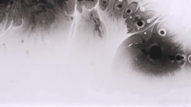 Benek sanatı. Sızdıran sıvı. Odaklanmamış siyah beyaz boya damlası su sıçraması soyut yaratıcı akrilik arka planda yüzer..