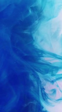 Dikey video. Mürekkep dumanı. Su damlasını boya. Odaklanmamış mavi pembe renk buharı sıçrama dalgası ışık soyut sanat arka planında hareketliliği ortaya çıkarıyor.