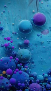 Dikey video. Sanat akışı. Kabarcık mürekkebi. Mavimsi, mor emülsiyon akrilik jel damlaları. Dalgalı karıştırma parçacıkları renkli soyut arkaplan.