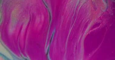 Sıvı dökülmesi. Akrilik sıçrama. Soyut arkaplana yayılan parlak parçacıkların odağından çıkarılmış pembe altın renkli simler..