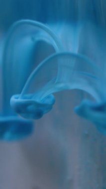 Dikey video. Sıvı sıçraması. Bulanık su dokusu. Odaklanmamış mavi renk parlaklığı soyut sanat ışığı arka planında sıvı duman dalgası oluşturur..