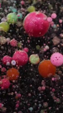 Dikey video. Renkli köpük. Sabun boyası. Işıldayan suyun içinde yüzen yuvarlak köpük baloncukları. Yaratıcı sıvı parçacıkları soyut arkaplan.