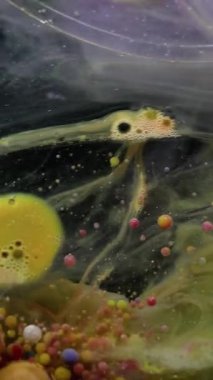 Dikey video. Sanat akışı. Pigment kabarcığı. Duman mermeri renkli mürekkep damlaları karanlık su soyut arka planında yüzer. Dalgalanan yaratıcı yağ karışımı.