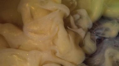 Duman girdabı. Köpüklü sıvı. Sarı bej, altın parıltılı boya akışı. Sanat sisi bulanık renk rengi su fantezi arkaplanı.