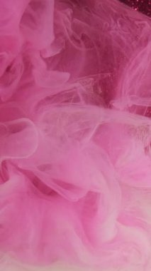 Dikey video. Sis bulutu arka planı. Boya rengi sis. Odaklanamayan pembe parıltı, ışıldayan soyut sanat ışığı üzerinde yüzen mürekkep deseni sisi sıçratıyor..