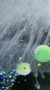 Dikey video. Yağ sıvısı. Boya çözülür. Sanat dumanı sıvısında akan renkli mürekkep kabarcıkları. Gizemli su peçesi soyut bulanık arkaplan.