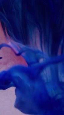 Dikey video. Boya rengi karışımı. Mürekkep arka planı bulanık. Odaklanmamış pembe parlayan sıvı damlalar akışkan duman dokusu soyut ışık dalgası.