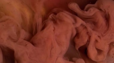 Dönen dokular. Soyut boya. Su parlaklığındaki pembemsi bronz mürekkep akrilik yaratıcı ıslak sanat üzerine sıçramış pigmentler..